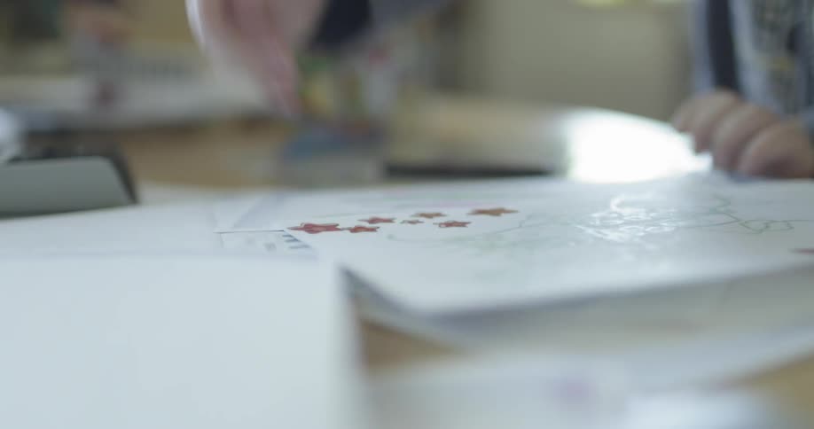 A child peels a sticker off of a sheet and places it on paper