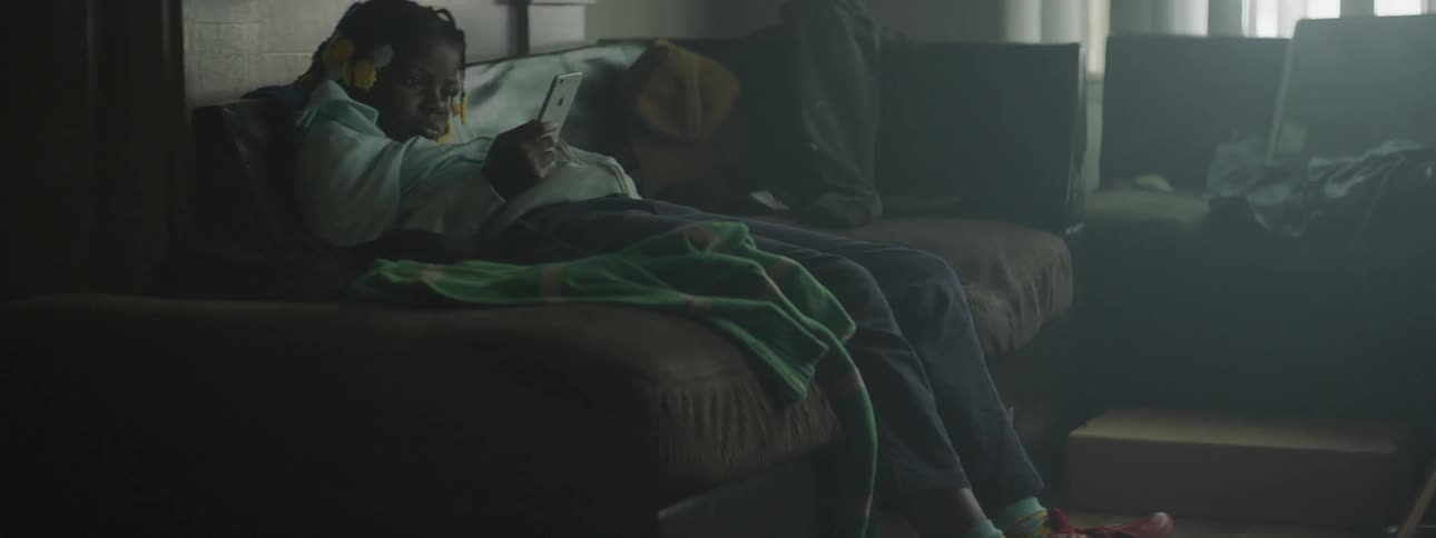 A child looks at a phone why lying down