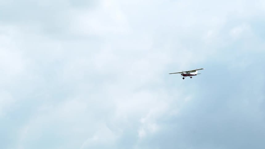 A small airplane flies in the air on a cloudy day