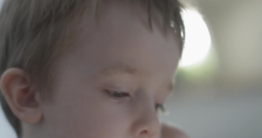 Close up of a small child's face as he looks down at something