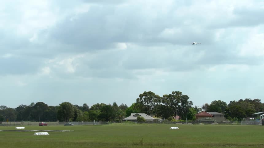 A plane flies over a wooded neighborhood