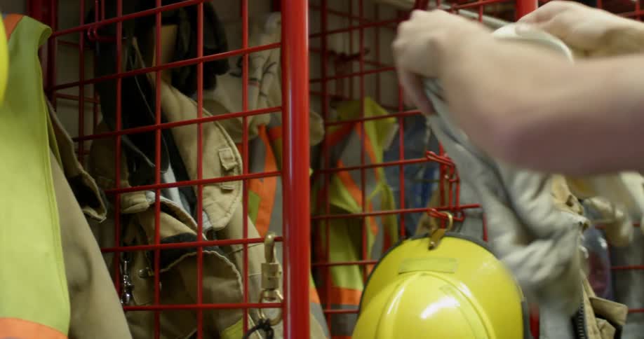 A fireman pulls on his overalls and takes something out of his coat