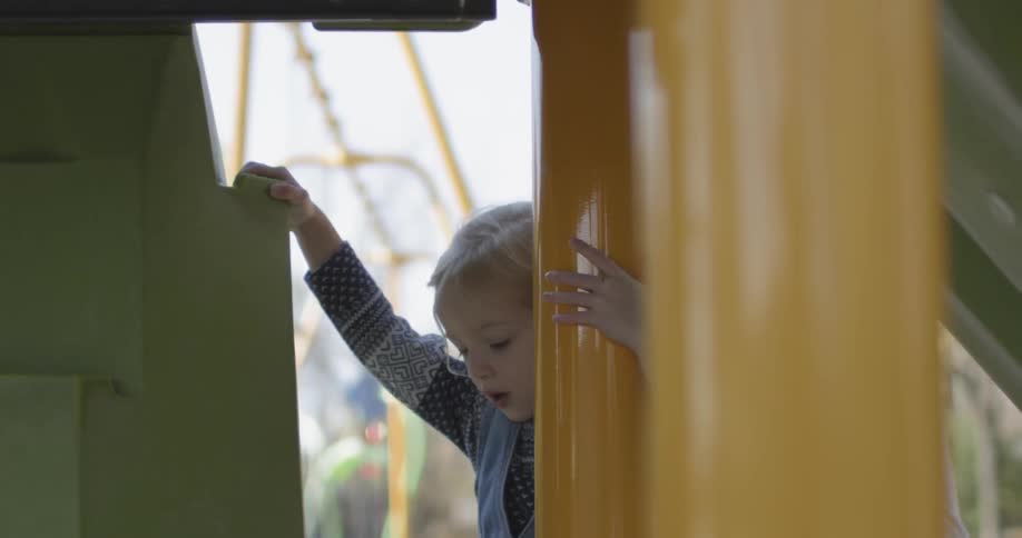 A woman watches a child playing at the park