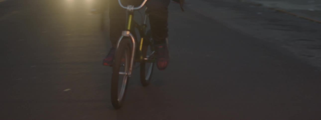 A young man rides his bike at dusk
