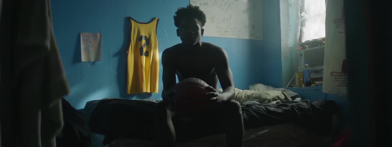 A man holds a basketball in his room