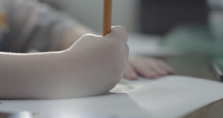 A child uses a pencil to draw with