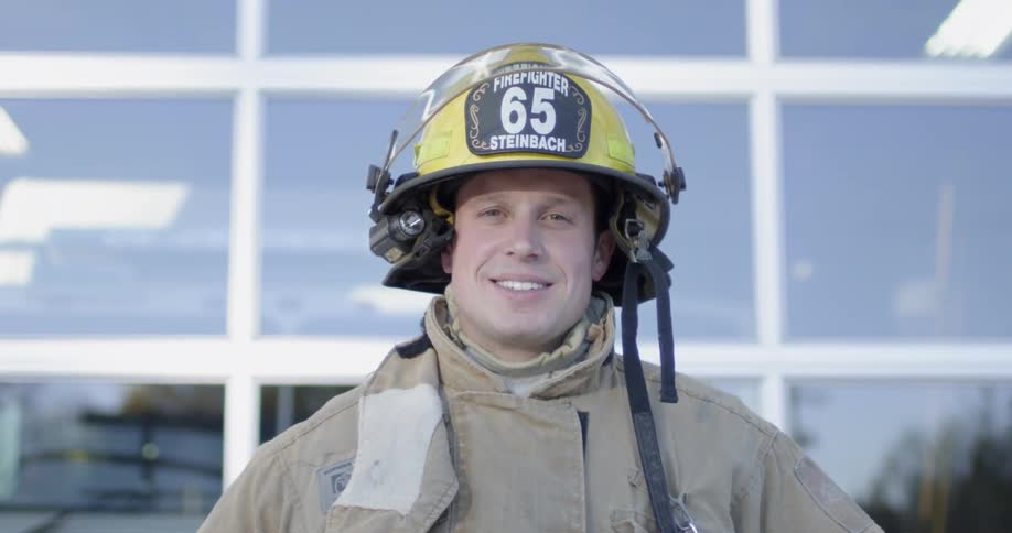 Firefighter stands outside the fire station smiling