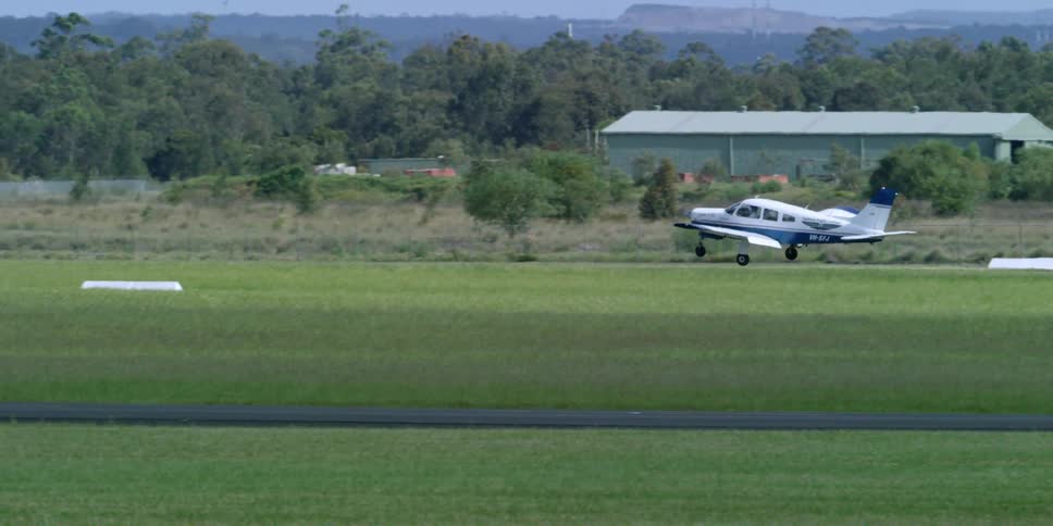 A small plane taking off from a small, rural airfield