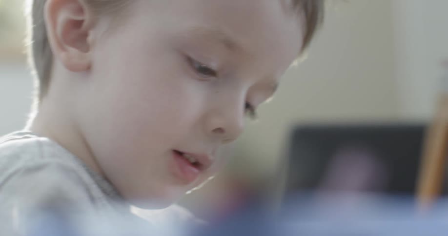 A young boy draws with a pencil