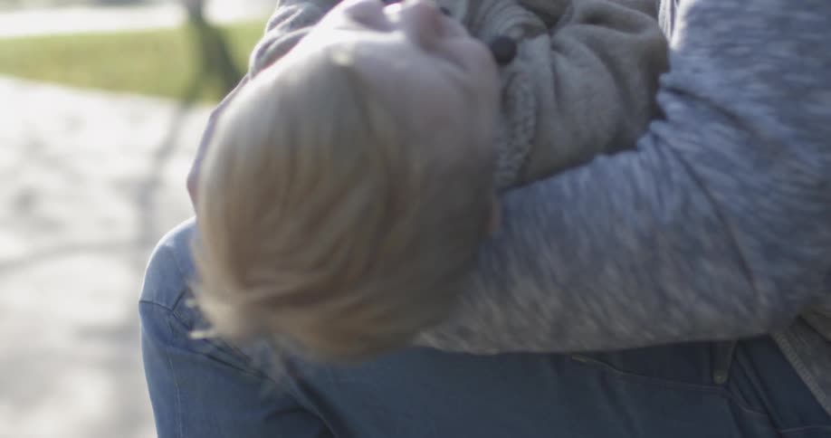 A man is laughing as he tickles his toddler son