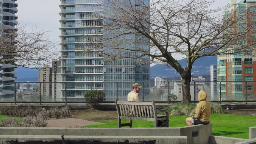 Two men are talking at rooftop park near a downtown city