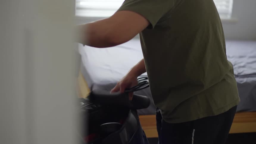 A man puts cables for his laptop into a bag