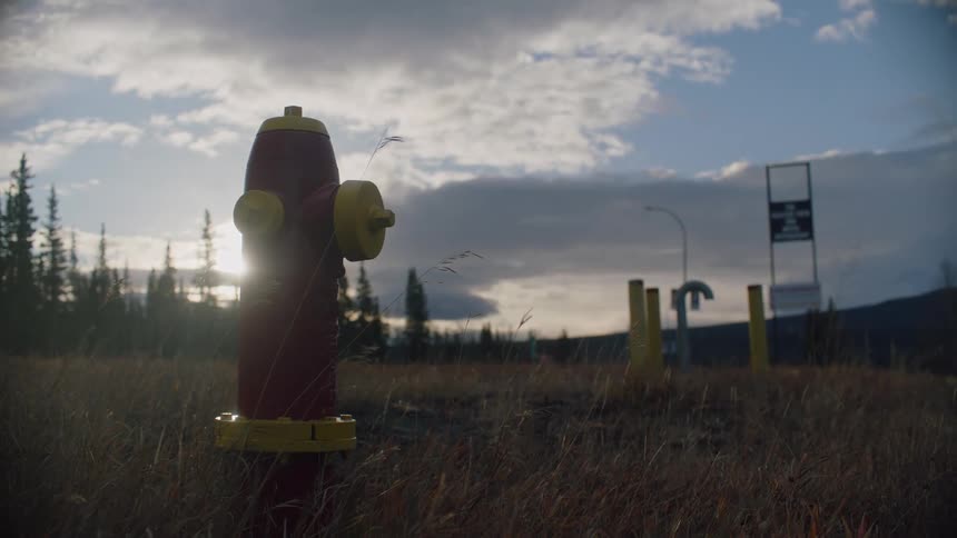 Close up of a red and yellow fire hydrant in the countryside at evening