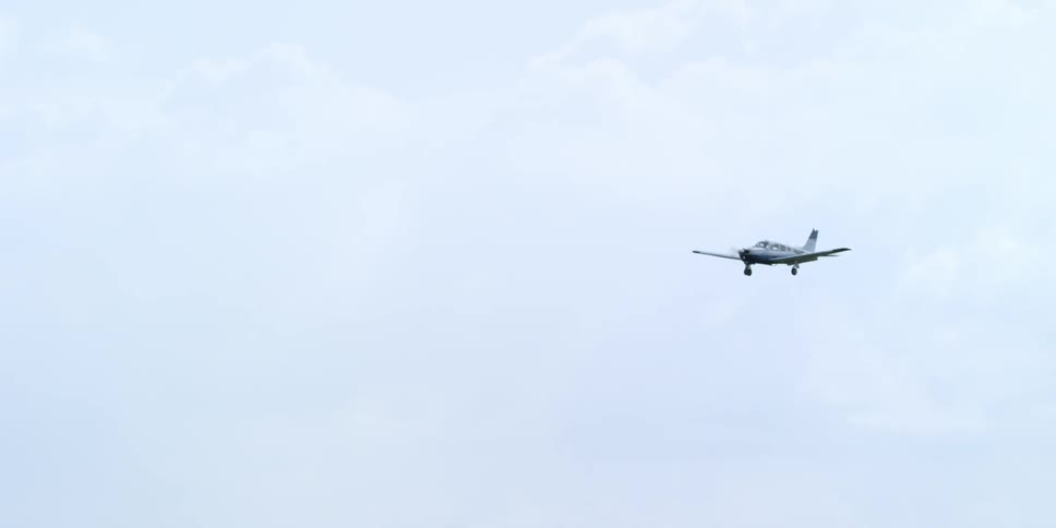 A small plane flying in a cloudy sky