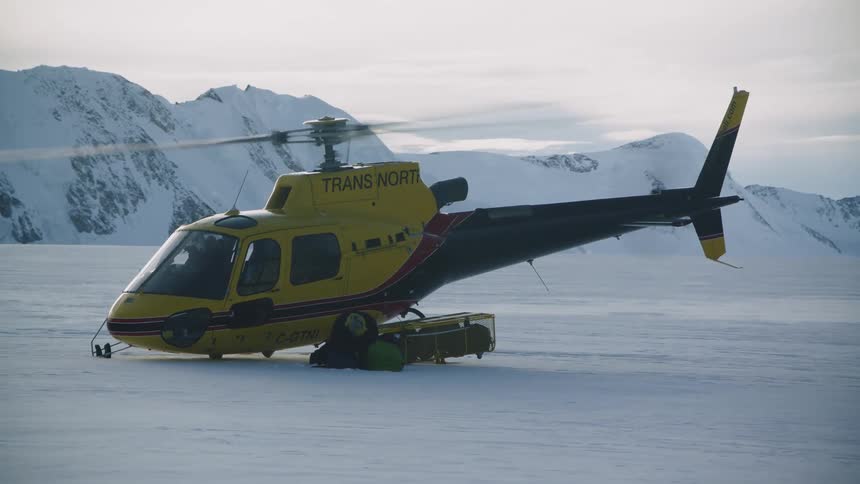 A person kneels down as the helicopter takes off