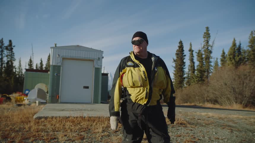 A man stands on a field by the forest