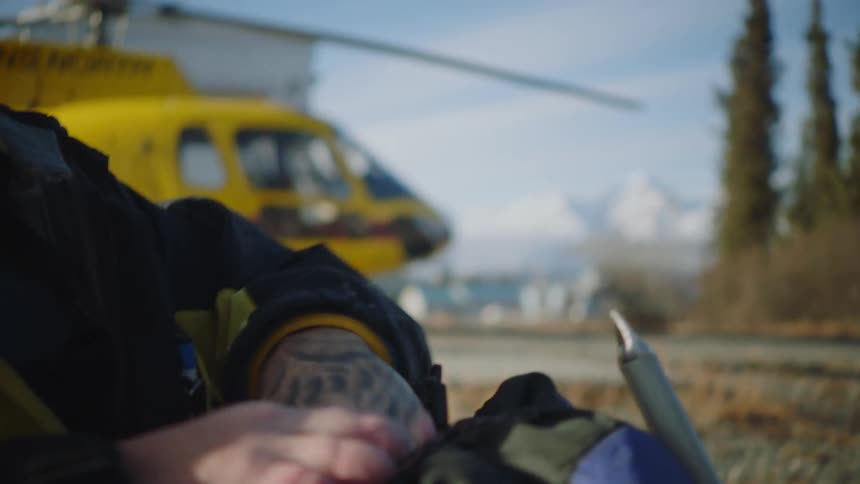 A man packs his bag by the helicopter