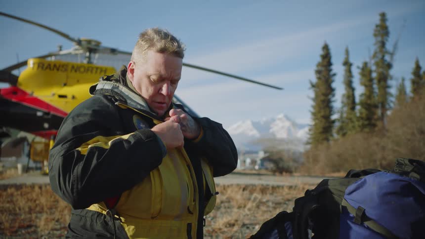 A man zips his coat up by the rescue helicopter