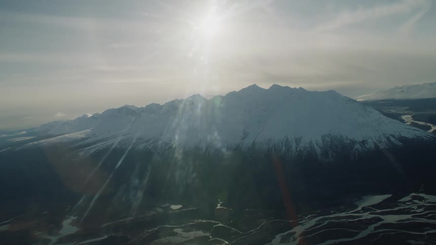 Aerial view of snow capped mountain range under shining sun