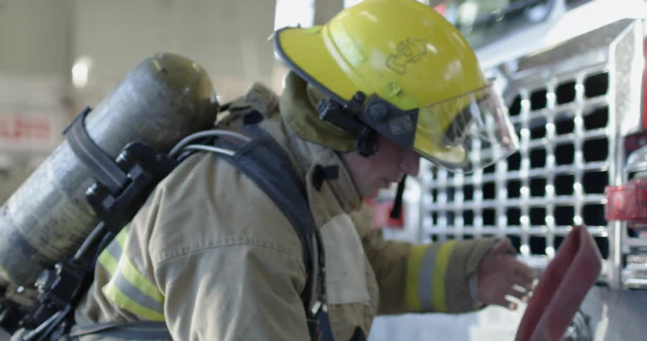 A fireman gets equipment ready next to a fire truck