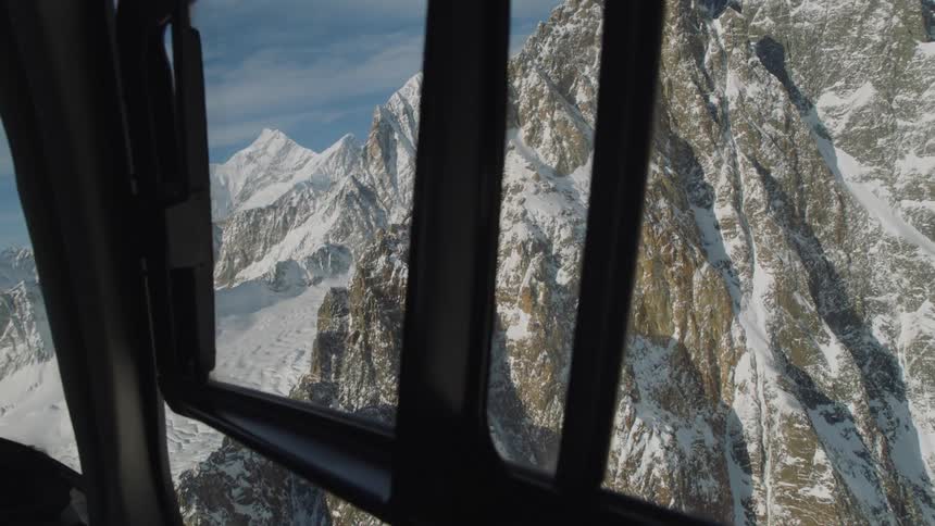 Snow covered mountain peaks and ridges from the inside of a helicopter