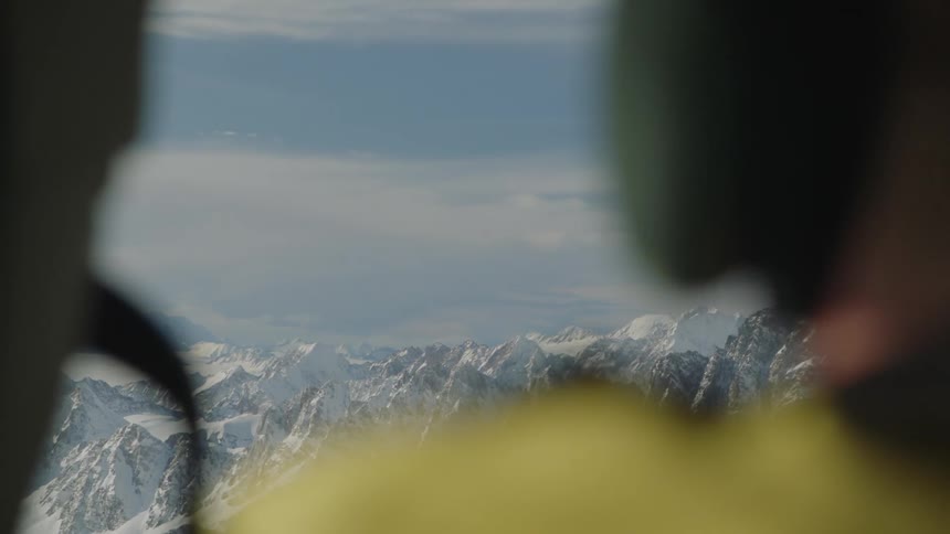 A man is standing outdoors in a mountainous landscape