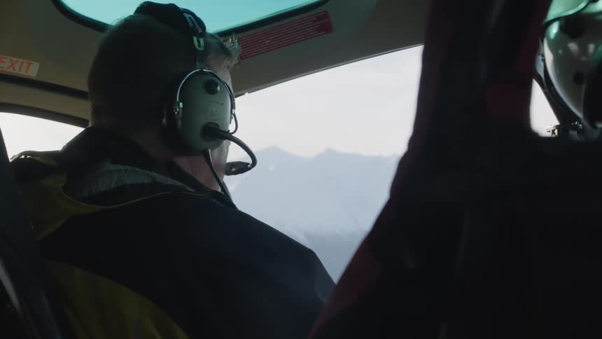 A male pilot is flying a private plane with a copilot whose only visible part is their helmet