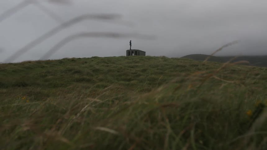 Silhouette of a young man standing over an abandoned building on a hill