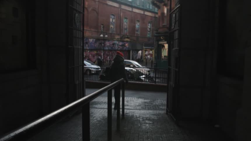 A woman walks out of an alleyway in a city