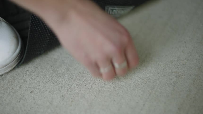 Close up of a person hurriedly picking a spare key from under the doormat