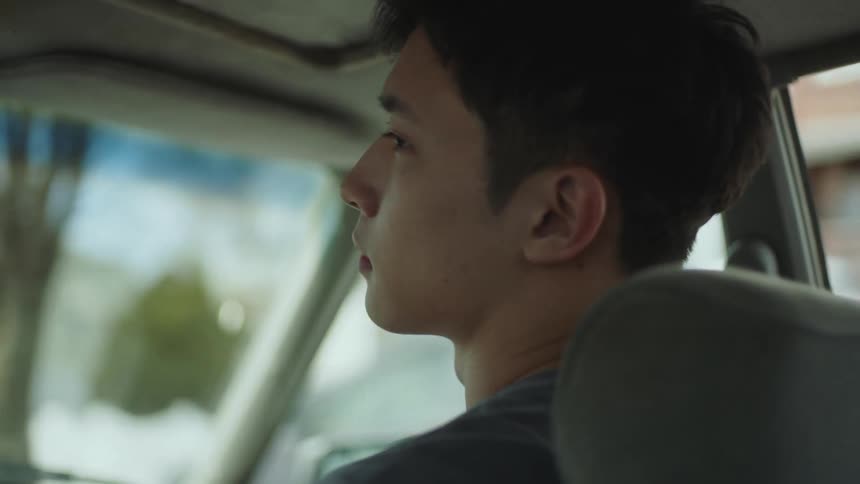Young man sitting on the passenger seat of a car driving on the city opens the door and jumps out