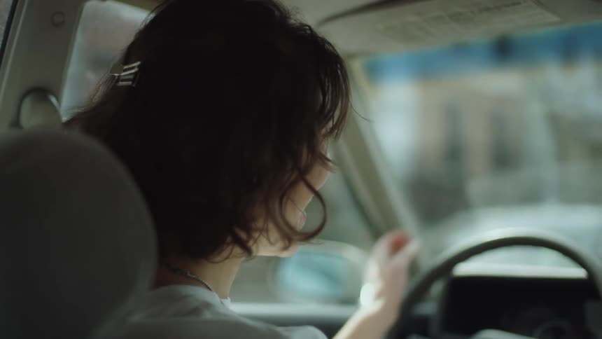 A female is driving a car through a suburban city