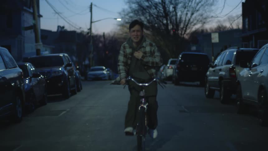 Sad man cycles down the street crying and weeping at dusk