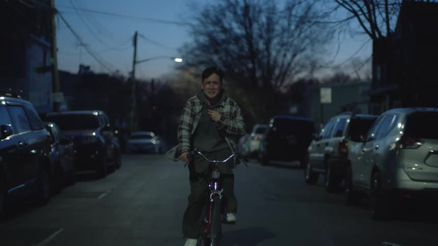 Male cyclist pedals down middle of street at night while crying