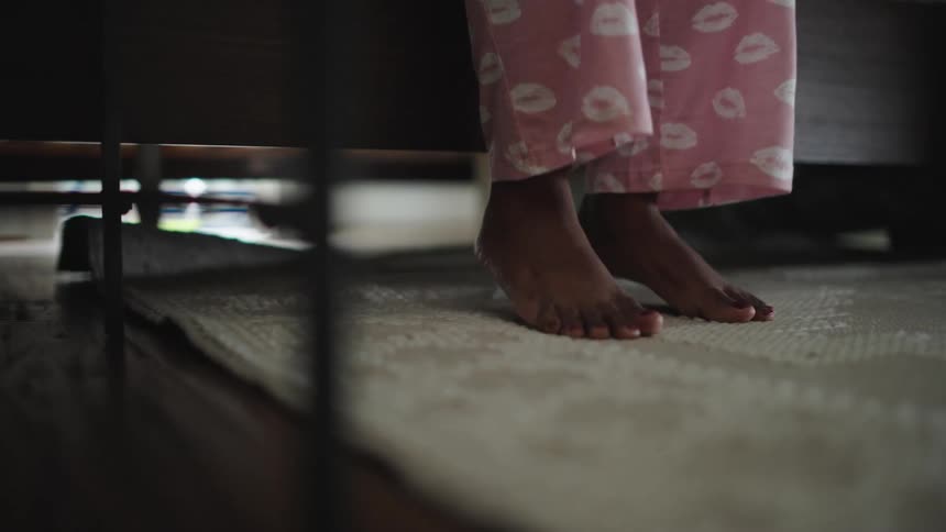 A view under the bed as a girl puts her feet down and walks off