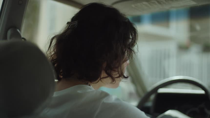 A woman is driving her car through a suburban city