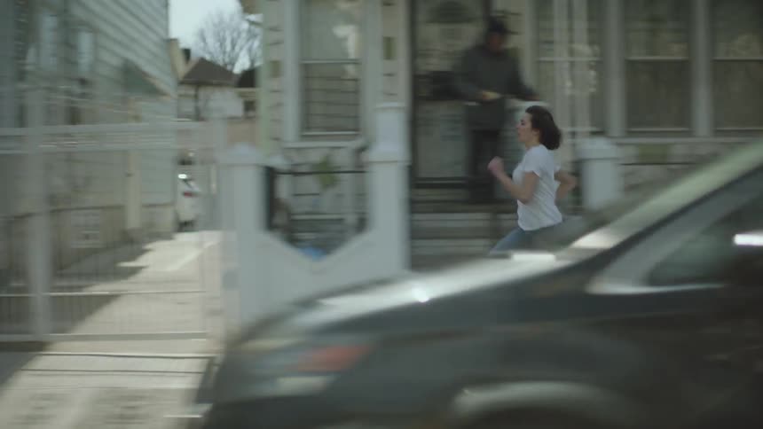 Woman with white t shirt jeans and shoes runs on the sidewalk in the street