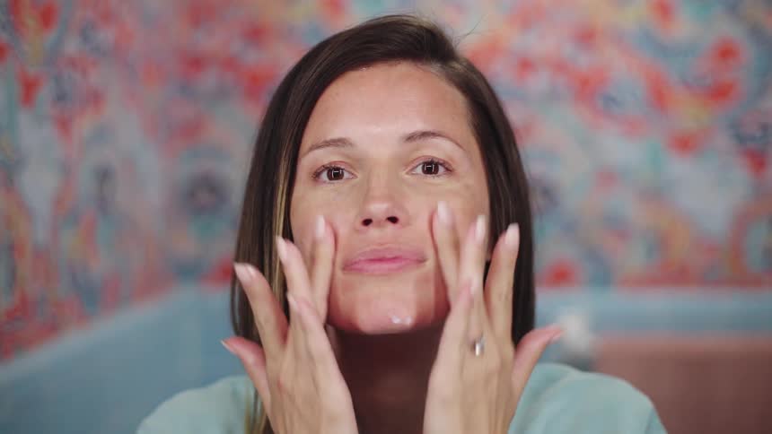 A woman is applying facial cream on her skin