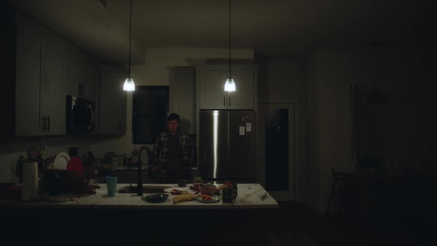 Young man making dinner in the kitchen at home suffers a brief panic attack