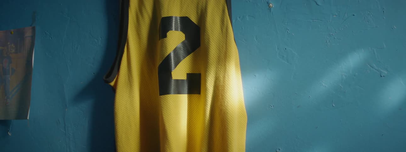 A jersey with the number 2 on it is hanging against a blue wall