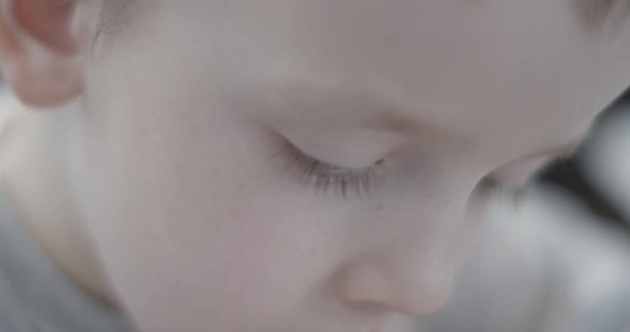 A little boy is looking down intently