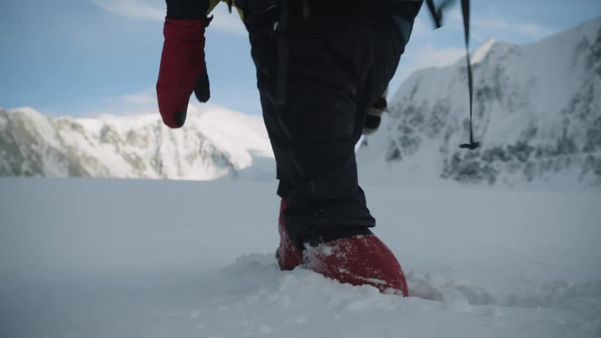 A person is hiking through heavy snow in an arctic landscape