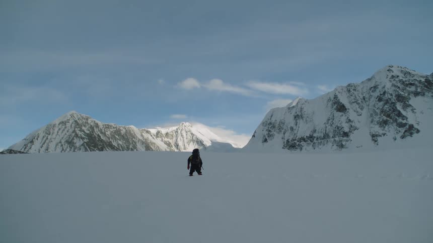 A person travels through the heavy snow by the mountains