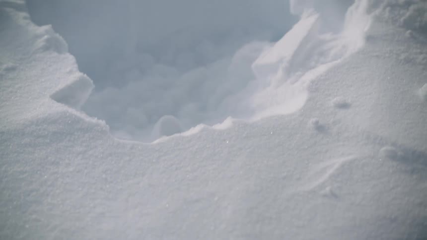 A person wearing red gloves shovels snow