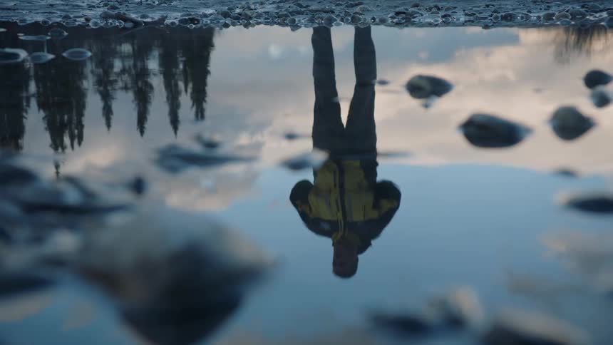 A close up of sitting water reflecting trees the sky and a person on the surface
