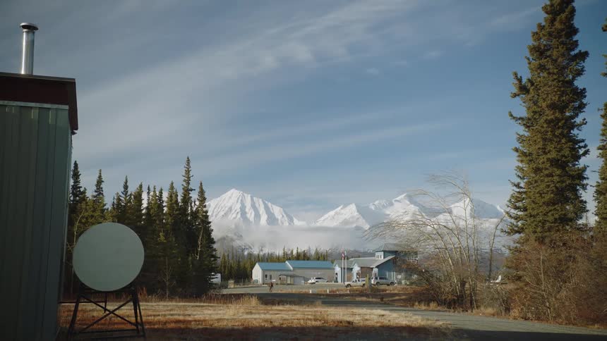 Small complex of buildings in the middle of a pine tree forest close to the mountains