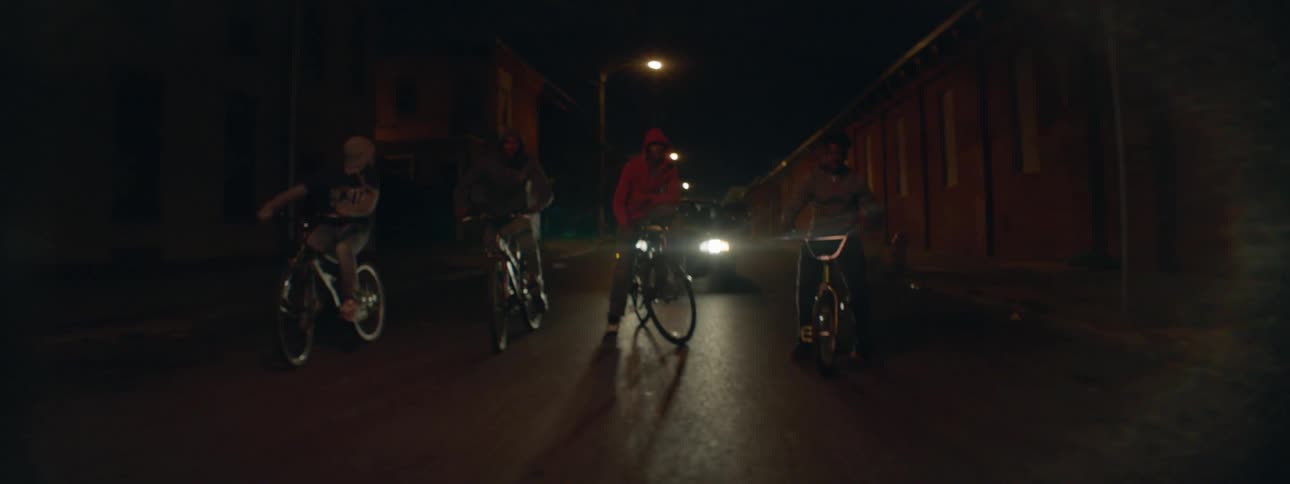 A car follows bicycle riders on a street at night