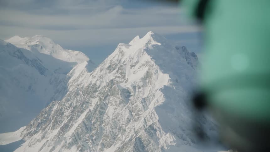 A person wearing a helmet looks across at snow covered mountains