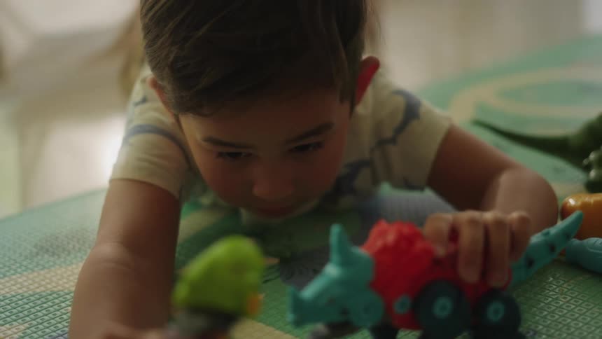 Little boy laying on floor playing with toys