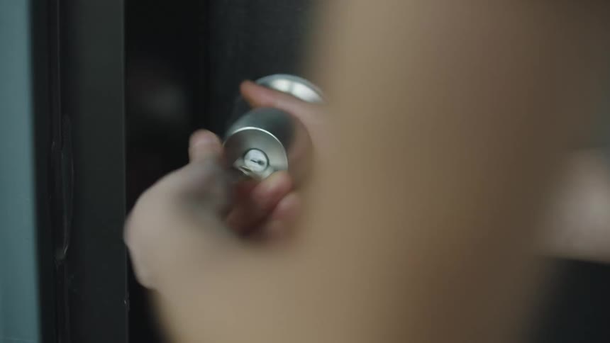 A person hands are seen using a key to unlock a door and going inside